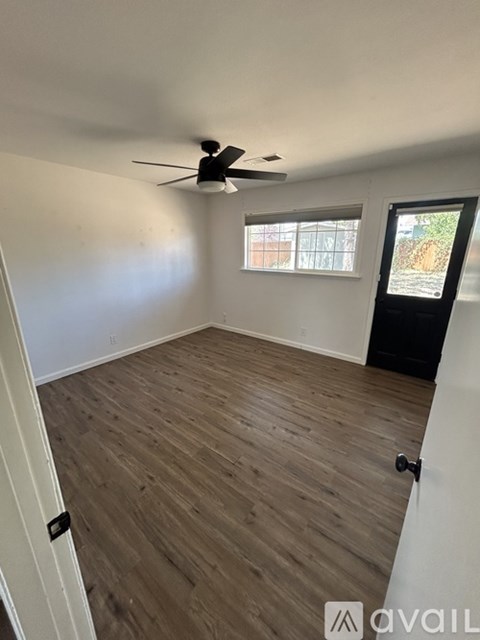 A room with a ceiling fan and wooden flooring.