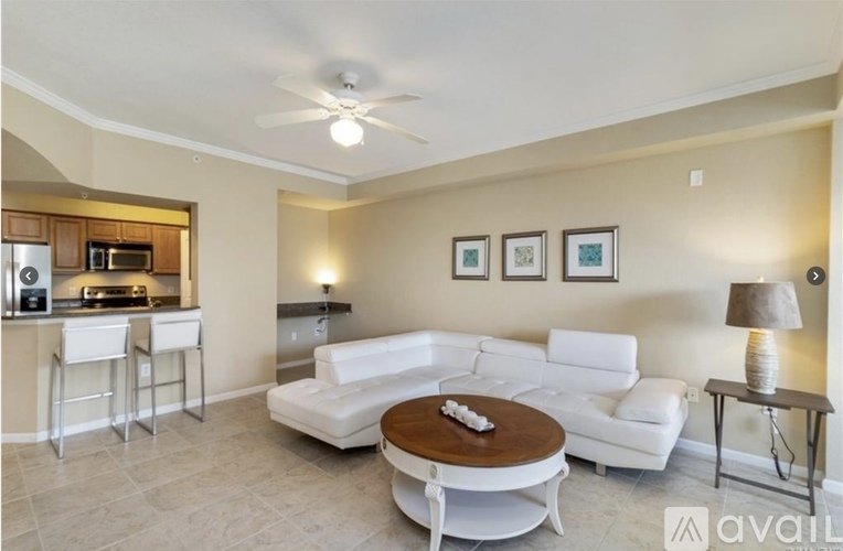 A living room with a white couch, a wooden coffee table, and a bar area with stools.