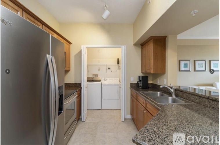 A kitchen with a stainless steel refrigerator and a granite countertop.