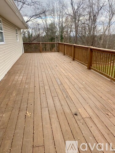 A wooden deck with a railing and a house in the background.