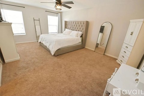 A bedroom with a large bed, a ceiling fan, and a window with blinds.