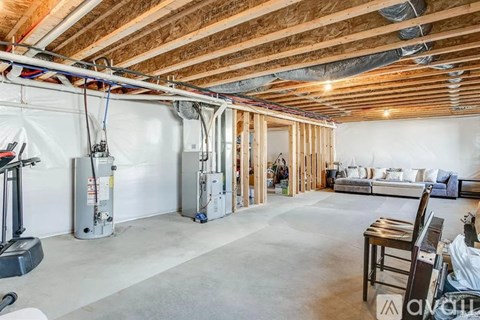 A room with a wooden ceiling and a white wall with a couch and a chair.