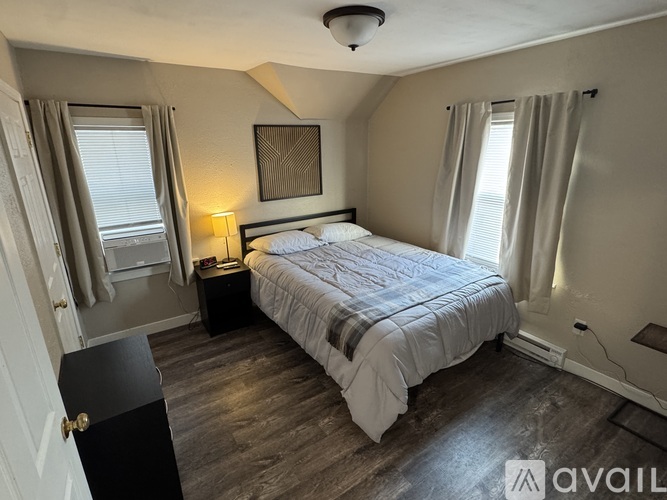 A bedroom with a bed, nightstand, and window.