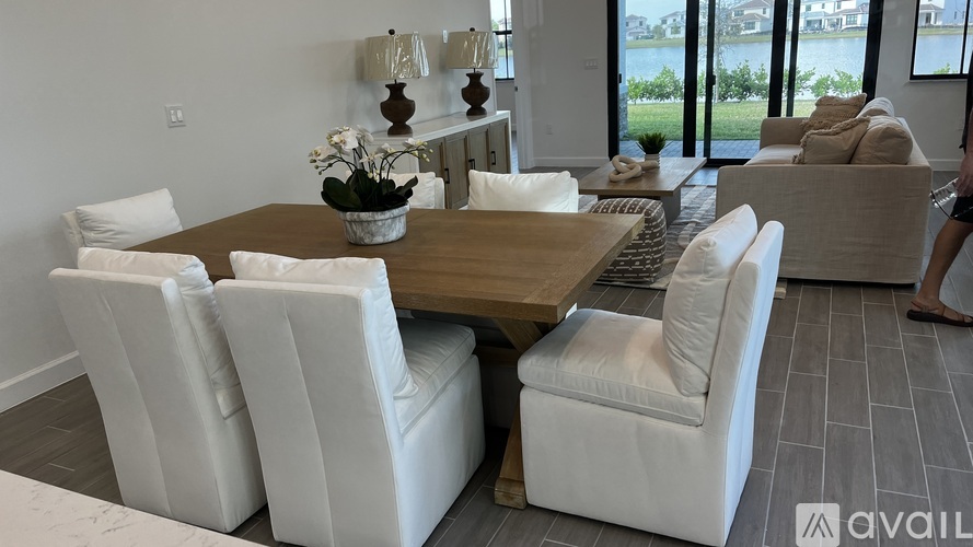 A modern dining room with a wooden table and white chairs.