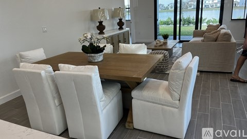 A modern dining room with a wooden table and white chairs.