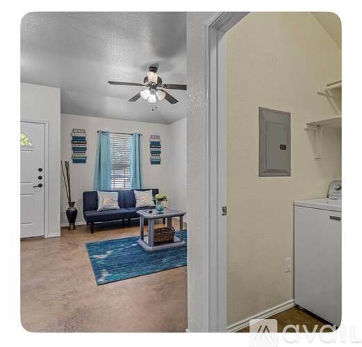 A living room with a blue rug and a white ceiling fan.