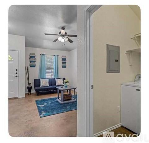 A living room with a blue rug and a white ceiling fan.