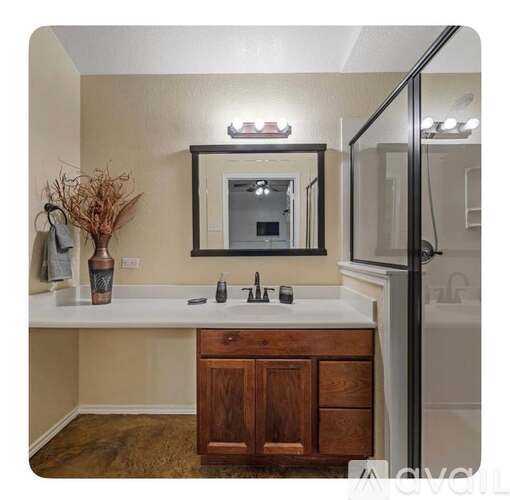 A bathroom with a white countertop and a mirror above it.