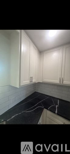 A kitchen with white cabinets and a black marble countertop.