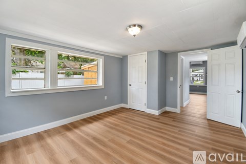 A room with wooden flooring and a window showing an outdoor view.