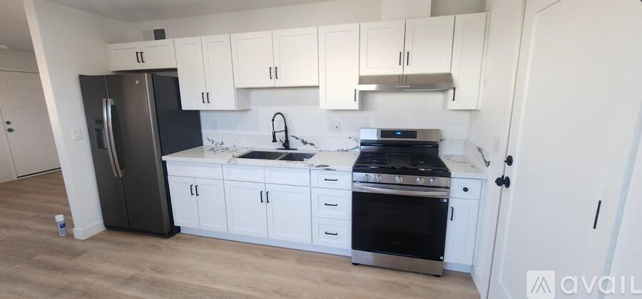 A kitchen with white cabinets and black appliances.