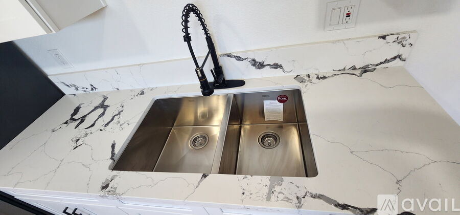 A kitchen sink with a black faucet and a marble countertop.