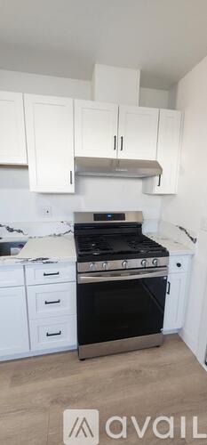 A kitchen with white cabinets and a black stove top oven.