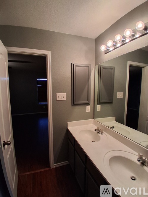 A bathroom with a vanity, sink, mirror, and lights.