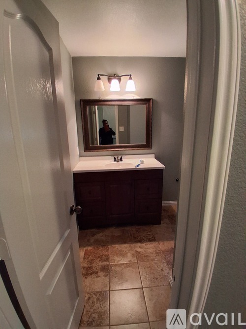 A bathroom with a brown vanity and a mirror above it.