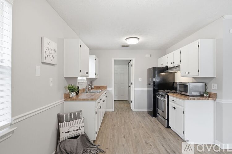 A kitchen with white cabinets and a wooden floor.