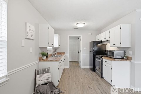 A kitchen with white cabinets and a wooden floor.