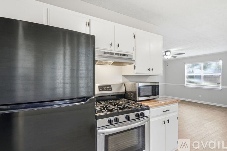 A black refrigerator is in a kitchen with white cabinets.