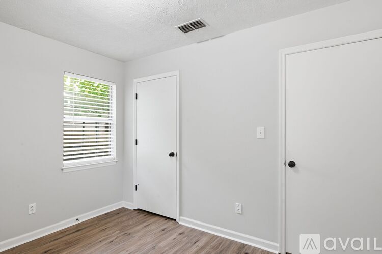 A room with a window, two doors, and a wooden floor.