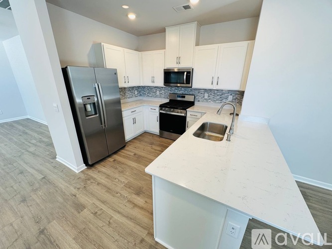 A kitchen with a refrigerator, microwave, oven, and sink.