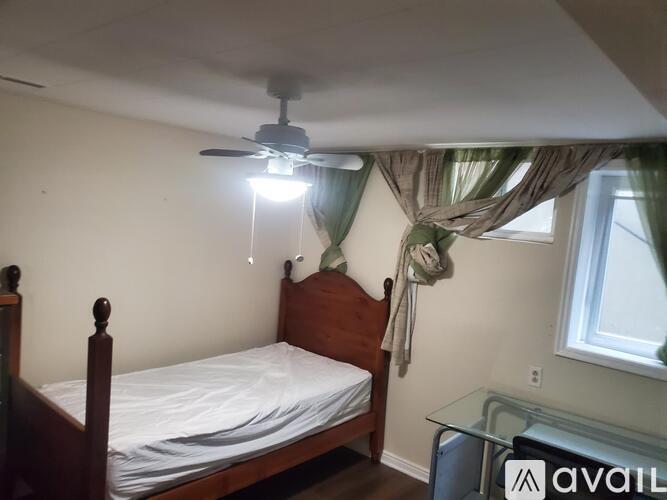 A bedroom with a bed, ceiling fan, and window.