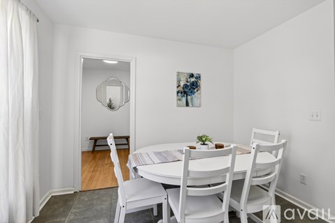 A dining room with a white table and chairs.