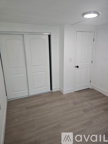 A room with a white door and a wooden floor.