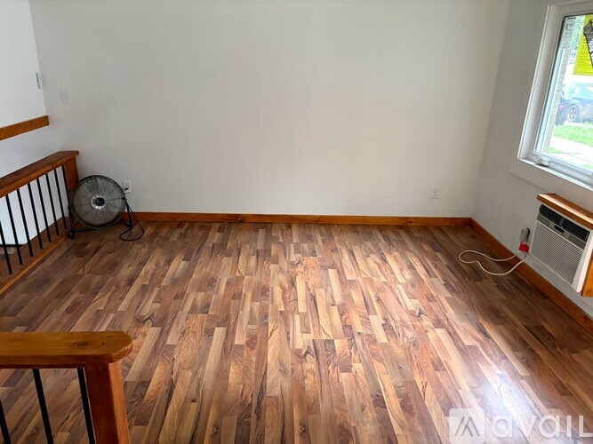 A room with wooden flooring and a window.