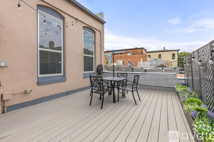 A wooden deck with a table and chairs is in front of a building.