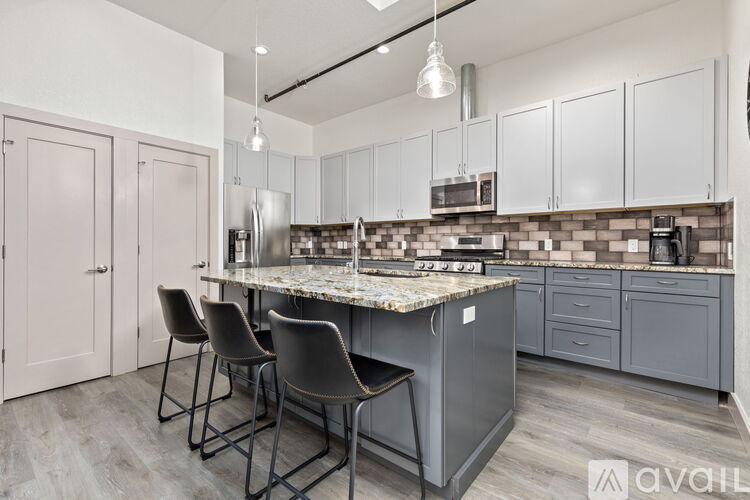 A kitchen with a marble countertop and grey cabinets.
