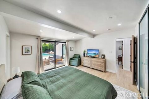 A bedroom with a large bed and a television in the corner.