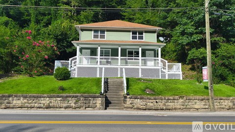 A house with a porch and a sign that says "available" in the front yard.