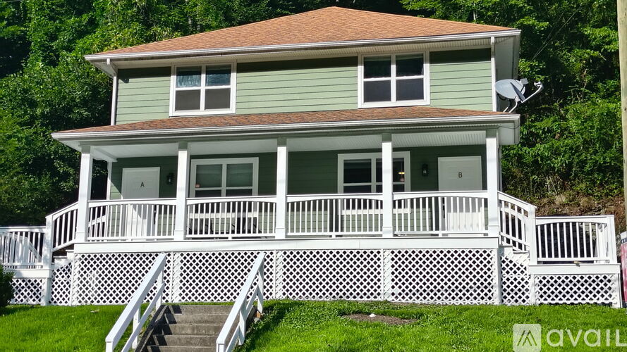 A house with a green siding and a white porch.