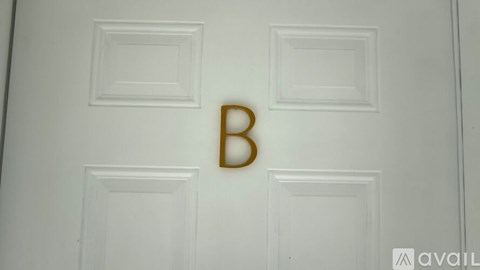 A white door with a gold letter B on it.