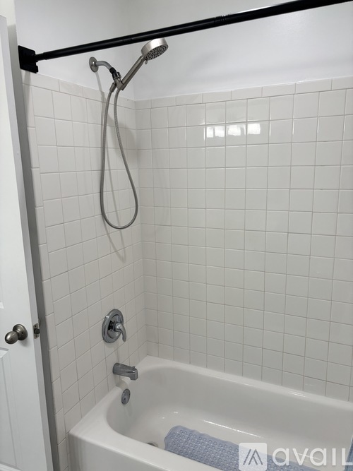 A white tiled bathroom with a black shower rod.