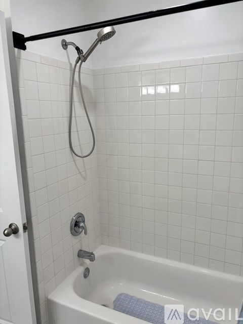 A white tiled bathroom with a black shower rod.
