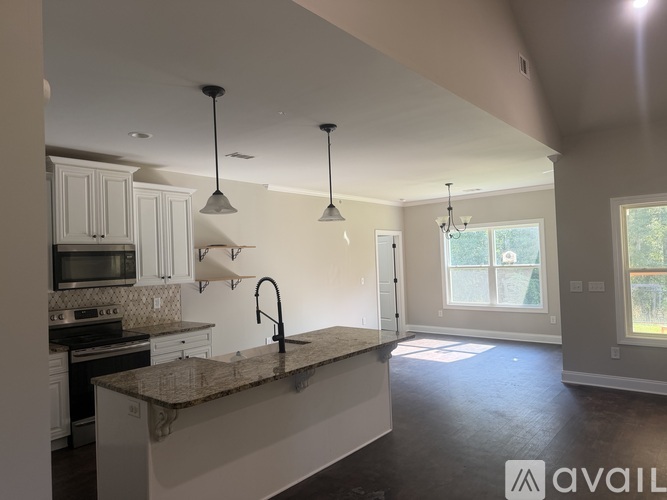 A kitchen with a granite countertop and pendant lights.