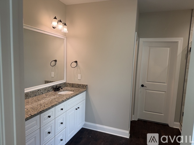 A bathroom with a sink, mirror, and cabinets.