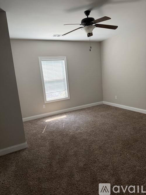 A room with a ceiling fan and a window with blinds.