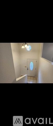 A hallway with a door at the end and a light fixture above it.