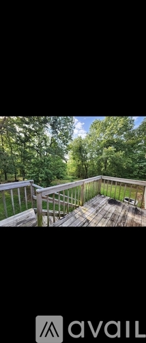 A deck with a railing and a view of trees.