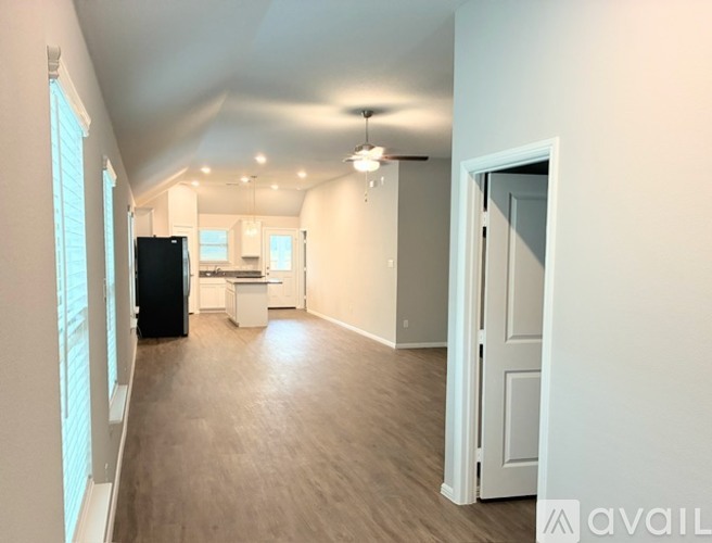 A spacious room with a kitchen area and a ceiling fan.