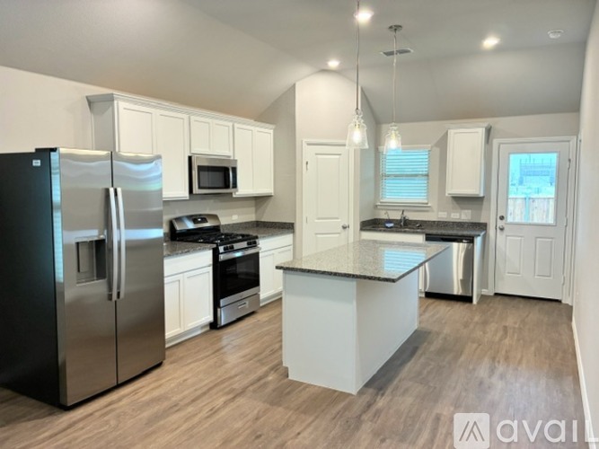 A kitchen with a black fridge, stove, and microwave.