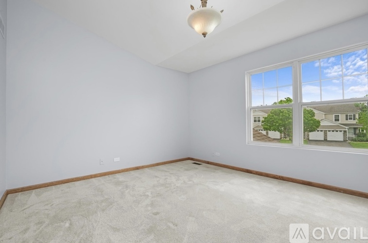 A room with a large window showing a view of a house and trees outside.