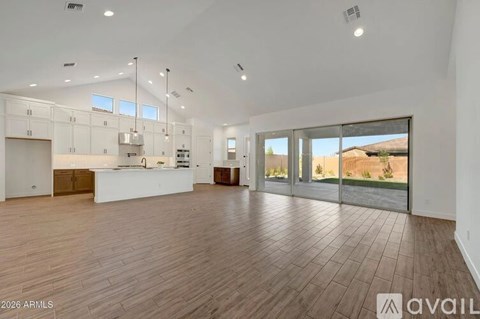 A spacious, empty room with wooden flooring and white walls.