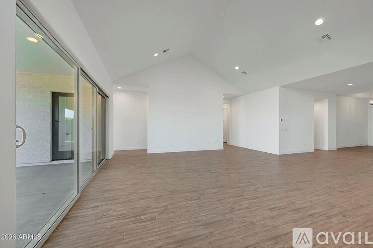 A spacious room with wooden flooring and white walls.