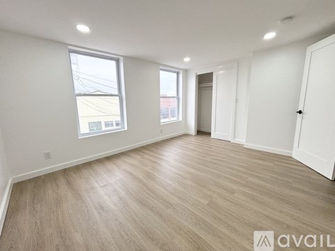 A spacious room with wooden flooring and white walls.