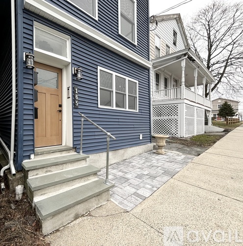 A blue house with a wooden door and a porch.