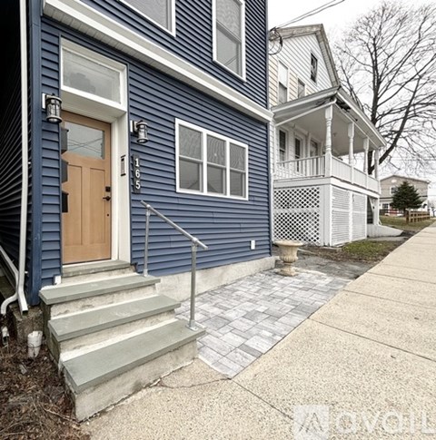 A blue house with a wooden door and a porch.