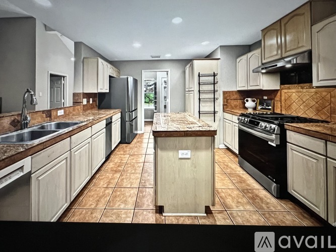 A kitchen with brown tiles and wooden cabinets is available for rent.